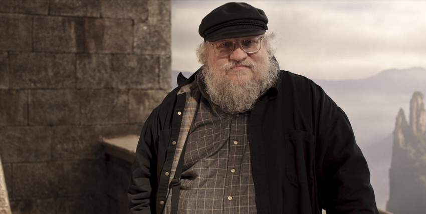 george r.r. martin in posa sopra il camminatoio di un castello - nerdface