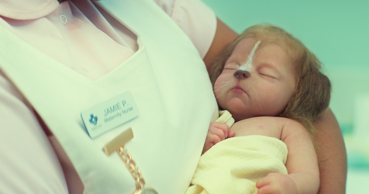 un neonato col musetto di daino dorme tra le braccia di un'infermiera - nerdface